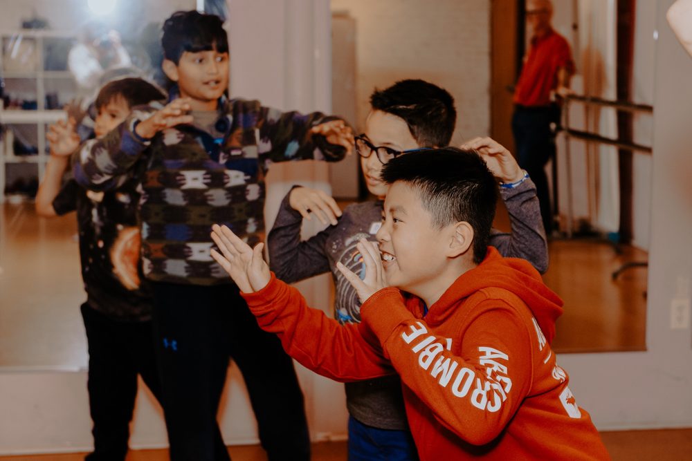 Children making dramatic poses in a group music and movement class